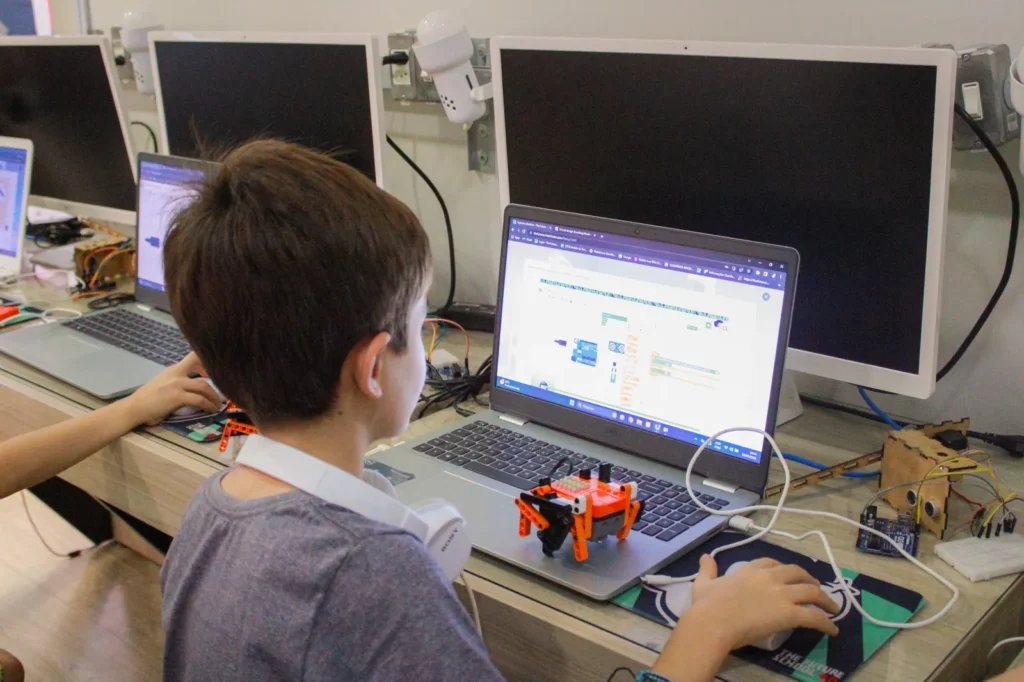 Aluno programando placa Arduino conectada ao notebook